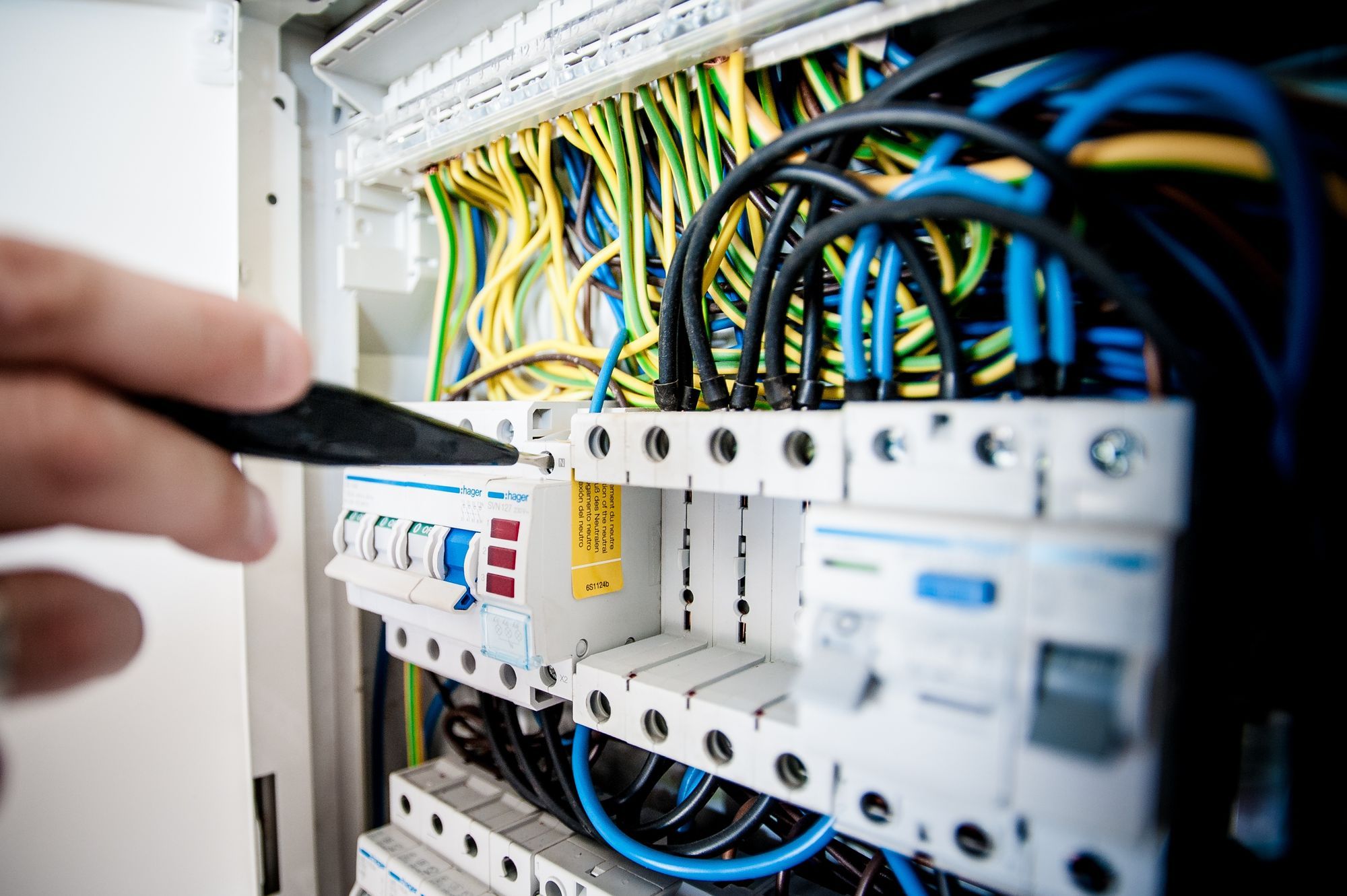 Rozvaděč s jističi a barevnými vodiči při kontrole elektrikářem